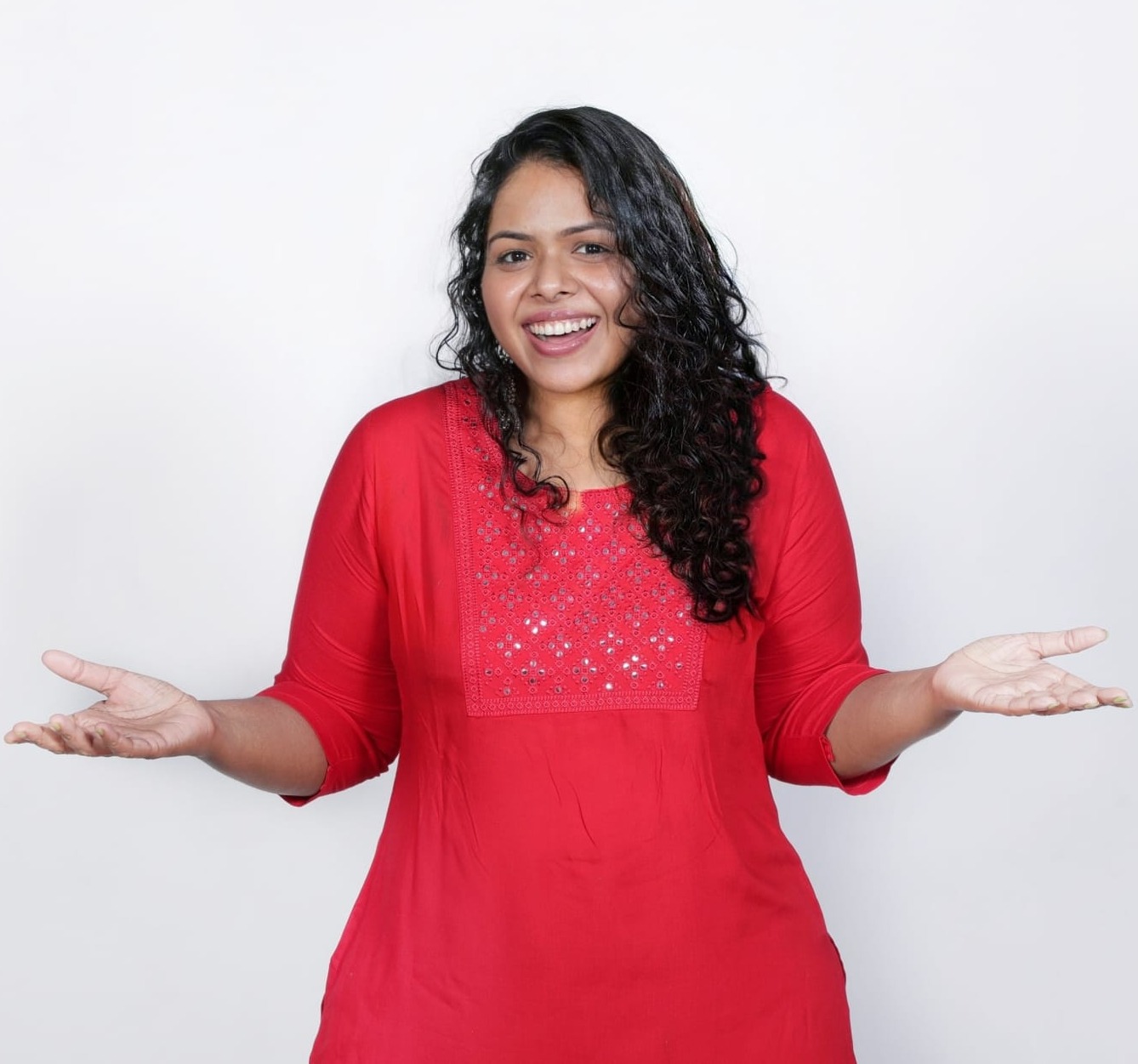 Bindhu smiling in her red kurta with open hands