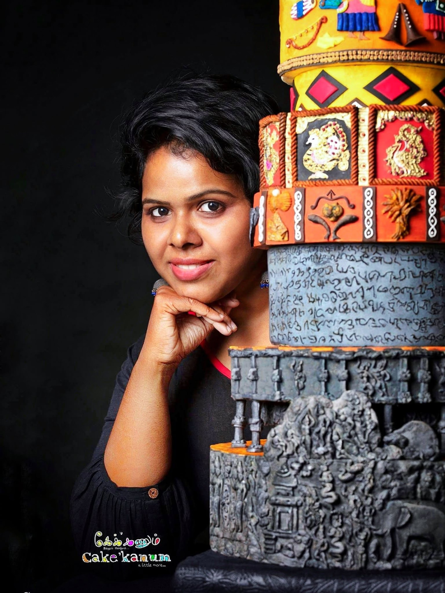 Bindhu beside a large multi-tier cake she decorated